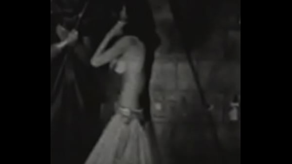 A slender dark haired in an exotic costume dances excitedly on the stage of an abandoned theater