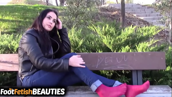 Shoeless dark-haired shows off her feet in public in the park
